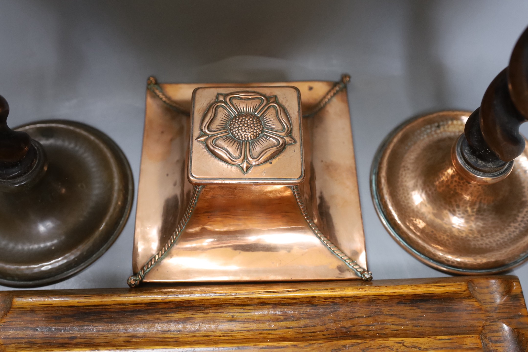 A copper Arts & Crafts inkwell, a pair of A Jones turned candlesticks and an early 20th century oak ink stand (4)